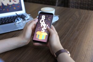 Bonus,Gaining.,Woman,Holding,Smartphone,On,Screen,At,Wooden,Table,