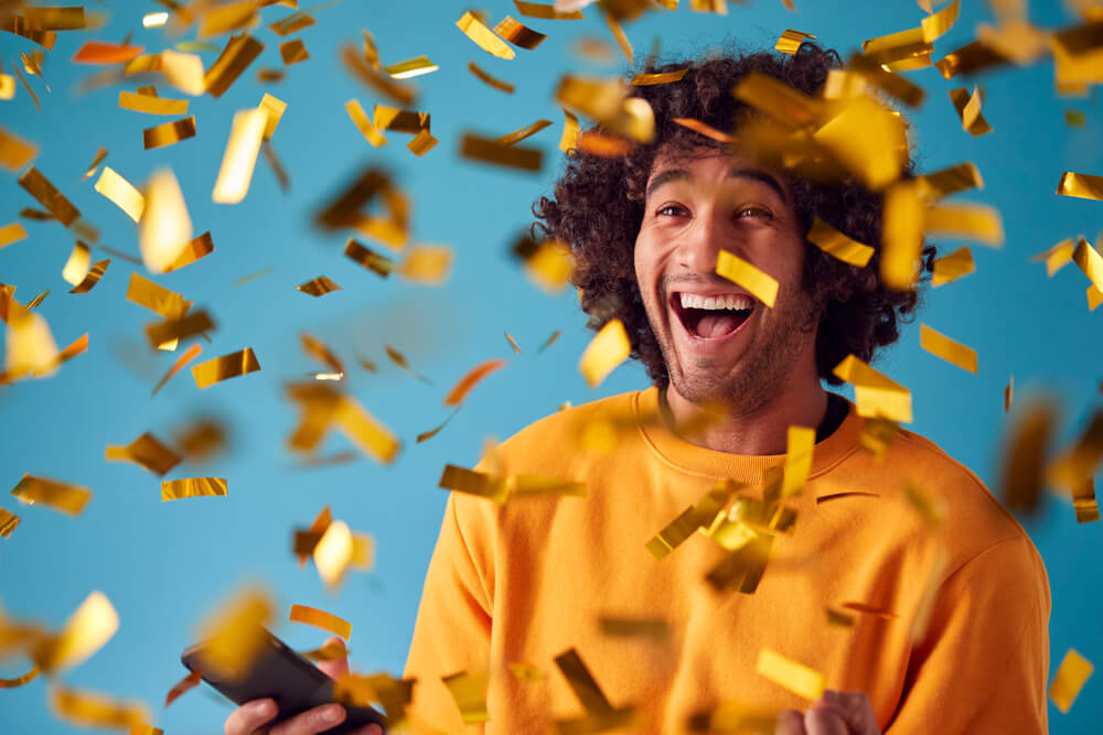 Celebrating,Young,Man,With,Mobile,Phone,Winning,Prize,And,Showered